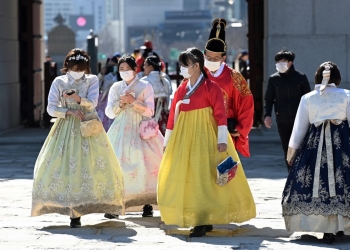 People in traditional Korean hanbok dresses wear face masks as they visit Gyeongbokgung palace in Seoul on February 23, 2020. - South Korea reported two additional deaths from coronavirus and 123 more cases on February 23, with nearly two thirds of the new patients connected to a religious sect. The national toll of 556 cases is now the second-highest outside of China. (Photo by Jung Yeon-je / AFP)