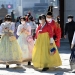 People in traditional Korean hanbok dresses wear face masks as they visit Gyeongbokgung palace in Seoul on February 23, 2020. - South Korea reported two additional deaths from coronavirus and 123 more cases on February 23, with nearly two thirds of the new patients connected to a religious sect. The national toll of 556 cases is now the second-highest outside of China. (Photo by Jung Yeon-je / AFP)